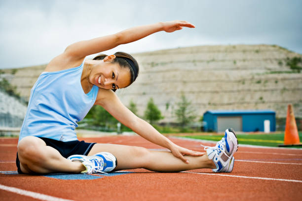 istock female runner on track stretching her arms and legs 157333127