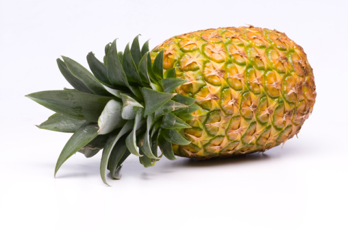 Top view of fresh cut pineapple with tropical leaves on dark blue background.