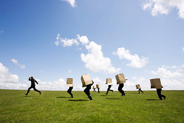 Outsider Businessman being chased by a herd of businessmen in boxes cloning photos stock pictures, royalty-free photos & images