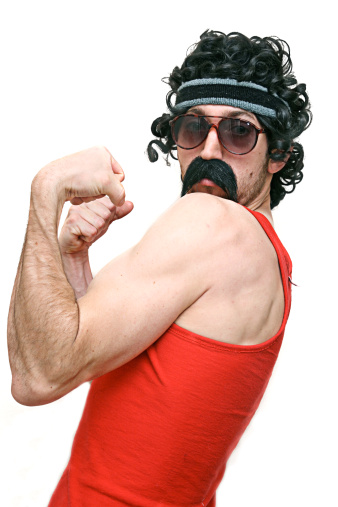 A weird guy with tinted glasses, handlebar mustache, and sweat band shows off his muscular biceps.  Isolated on a white studio background.