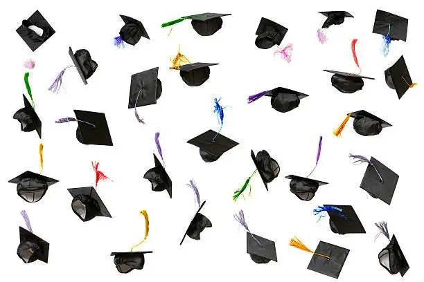 Lots of flying graduation caps isolated on white.