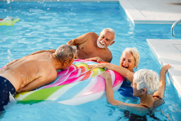 istock Cheerful seniors having fun on a pool raft in summer day. 1573339555