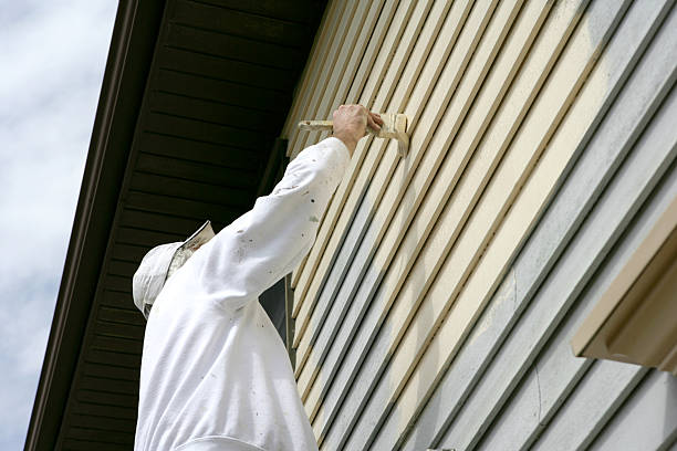 Man in white coveralls painting the outside of a house stock photo
