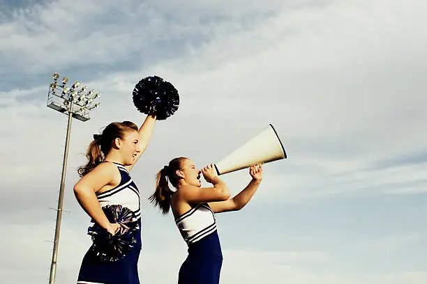 Two female cheerleaders rally the crowd for a score. Plenty of room for copy.