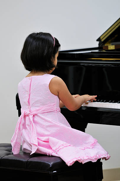 Little girl playing piano  girl playing piano stock pictures, royalty-free photos & images
