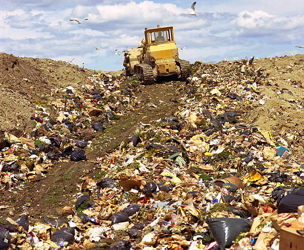 A bulldozer driving up a hill of garbage stock photo