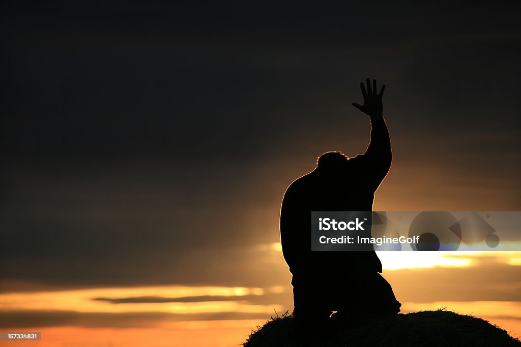 Silhouette of a Man Seeking God A silhouette of a man holding his hand toward heaven. This image has a strong religious or Christian theme. Other themes are: praise and worship, spirituality, deliverance, healing, forgiveness, grace, salvation, faith, humility, love, hope, and meditation. This is an unrecognizable man in his 30s.  Praying Stock Photo