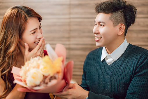 Young man greeting his girlfriend on Valentine's Day at restaurant