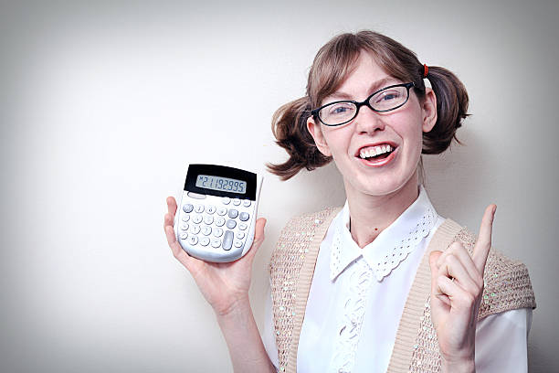 Nerd Girl With Calculator and Copy Space Nerdy young woman makes a math discovery on her calculator. Horizontal with copy space. nerd teenager stock pictures, royalty-free photos & images