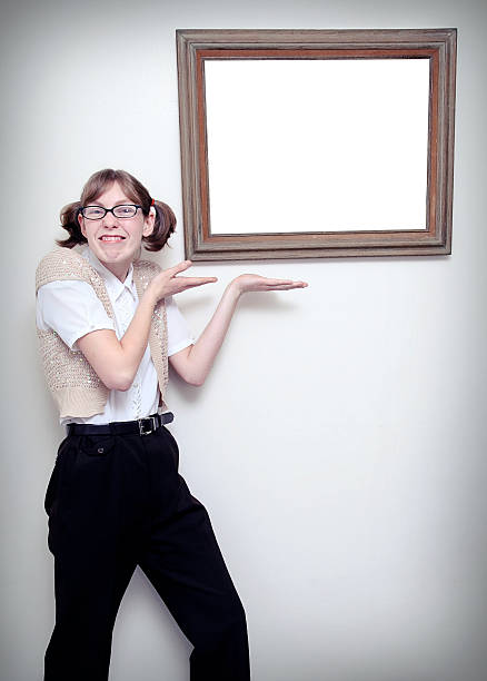 Nerdy young woman presents a blank picture frame, white with copy space.