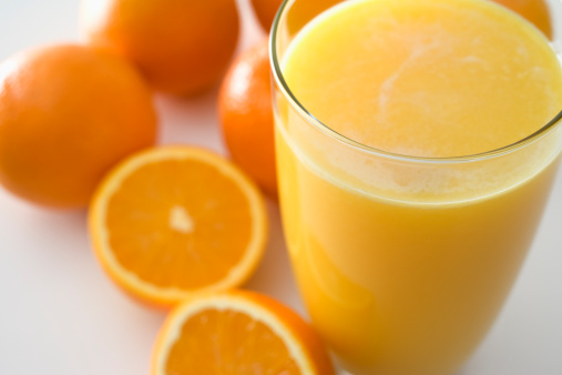 Two healthy and delicious glasses of carrot-orange juice in a light and bright kitchen counter scene with copy space