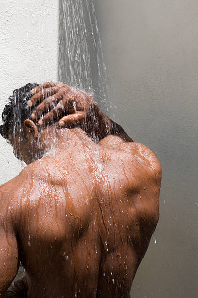 athletic, tanned  male back under the shower stock photo
