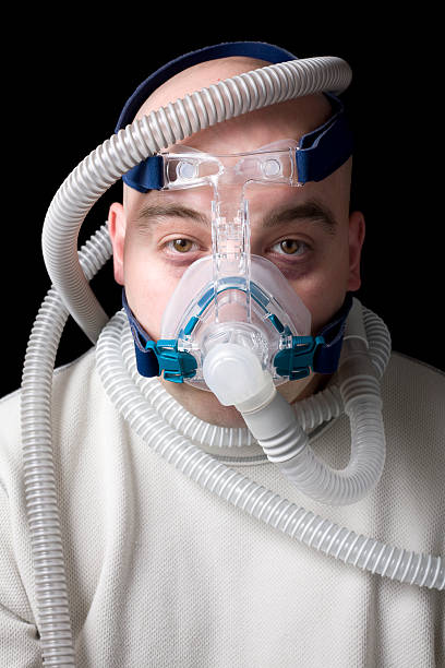istock Man wearing CPAP machine with tubes wrapped around him 157336312
