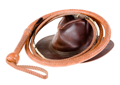 A leather bullwhip and a man's hat on a white background.