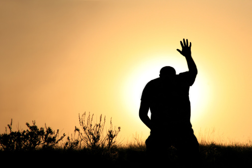 A man lifts his hand towards heaven. Silhouette, rear view, unrecognizable person. Additional themes include salvation, god, praise and worship, holiness, righteousness, faith, sin, forgiveness, gratitude, meditation, prayer, self, asking, pleading, hope, heaven, healing, spirituality, balance, religious, and Christianity. 