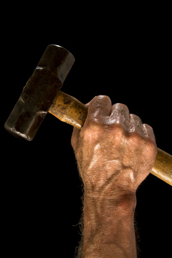 Man holding sledgehammer against black background.