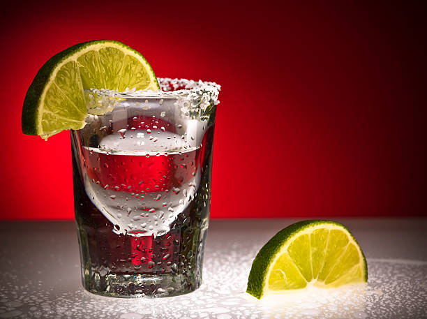 nahaufnahme von einem schnapsglas and limes - tequila slammer stock-fotos und bilder