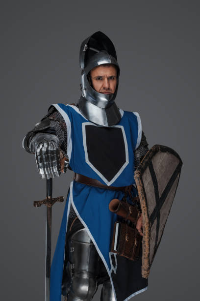 istock Valiant medieval warrior wearing armor and blue surcoat 1573387439