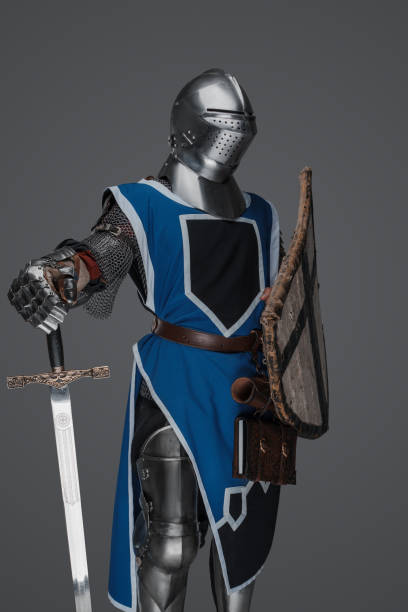 istock Medieval guard dressed in armor and blue surcoat holding a sword 1573388469