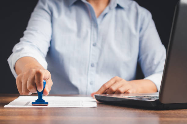 istock Businessman stamping approved on documents while sitting working in the office 1573392588