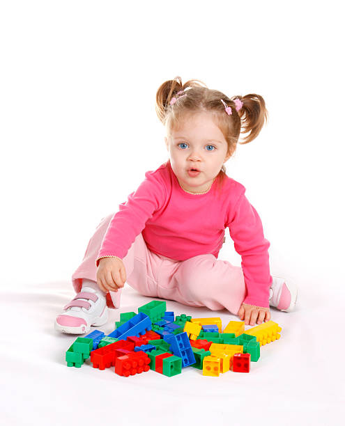 mignonne petite fille jouant avec des blocs sur fond blanc - preschooler child offspring purity photos et images de collection