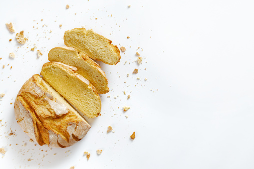 Sliced fresh bread with crumbs and fresh bread slices isolated on white background with copy space top view