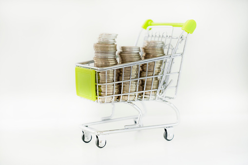 Many coin in mini shopping cart on white background