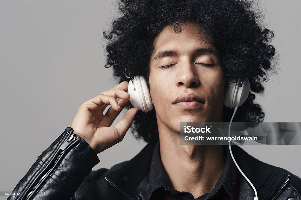 afro music headphones portrait of a dj man listening to music on headphones with afro hairstyle isolated on grey background Adult Stock Photo