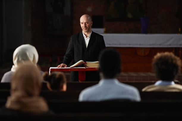 istock Preacher reading prayer for people in church 1573424605