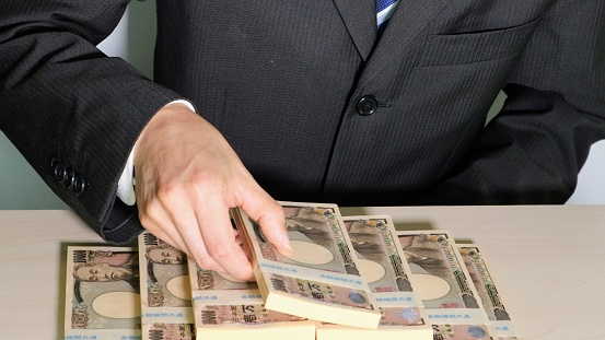 Photo of a businessman piling up wads of money