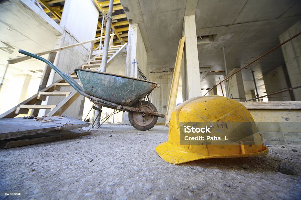 Schutzhelm und Einkaufswagen auf Beton Boden innen unversäuberten Gebäude - Lizenzfrei Baustelle Stock-Foto