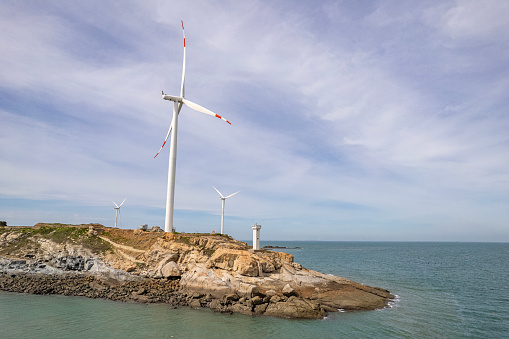 Wind generator on the edge of the small island cliff surrounded by sea water