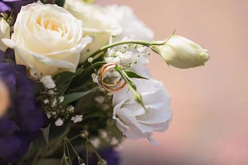wedding rings on a wedding bouquet of white flowers.