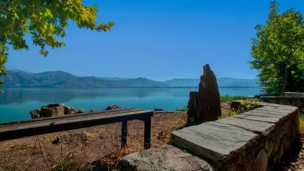 A scenic view of a wooden bench on the shore of Lake Kastoria, Greece