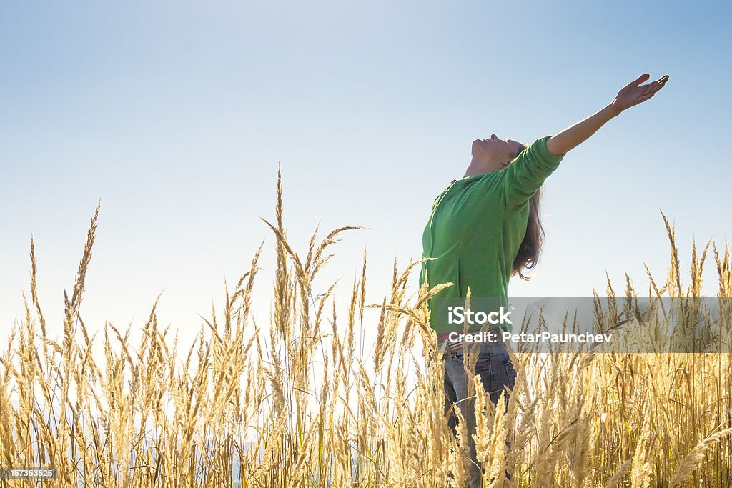 Happy in the grass Happy young girl raising her arms with bliss and joy in the tall grass on a beautiful sunny day Hard Liquor Stock Photo