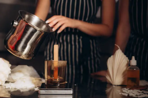 Woman making candles at white table, closeup.