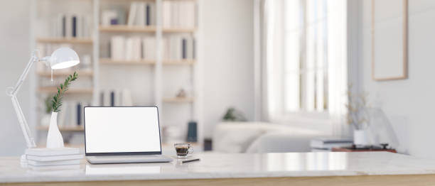 istock A laptop mockup on a tabletop with a blurred modern white living room as a background. 1573559322