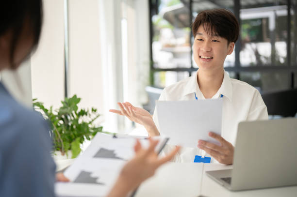 istock A smart Asian male office worker is discussing work with his colleague 1573560416
