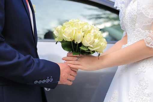 The bride and groom are holding a wedding bouquet of white roses