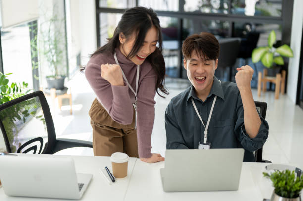 istock Two overjoyed Asian office employees are rejoicing and celebrating their project success 1573562031