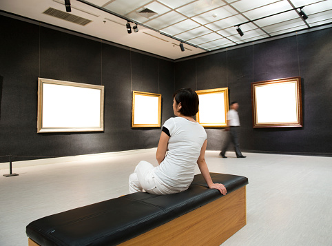 woman looking at white frames in an art gallery.