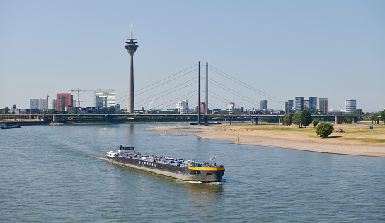 Düsseldorf, Germany- June 15, 2023: Skyline of Düsseldorf with Rhine Tower, a barge in the foreground.