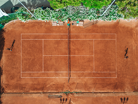 Aerial drone point of view of a clay court during a professional tennis tournament.