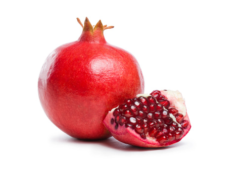 Studio shot of fresh ripe pomegranate whole and part with seeds.