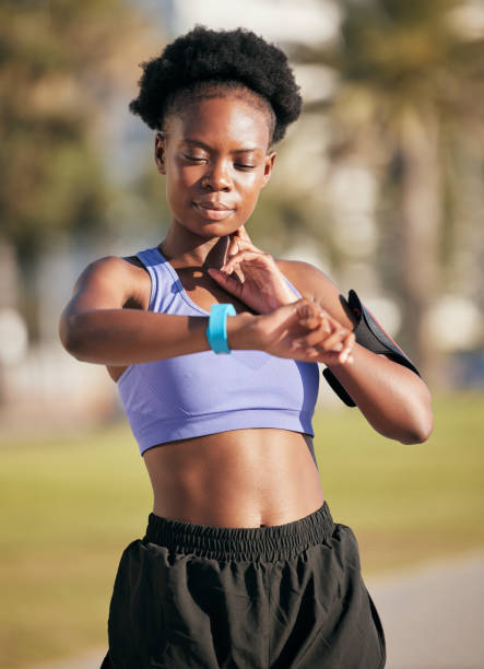 Fitness, pulse and female athlete on a workout with smartwatch for running outdoor in nature. Sports, exercise and African woman monitoring her heart rate for cardio training for race or marathon. fitness, pulso y atleta femenina en un entrenamiento con reloj inteligente para correr al aire libre en la naturaleza. deportes, ejercicio y mujer africana monitoreando su ritmo cardíaco para entrenamiento cardiovascular para carrera o maratón.