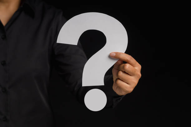 istock Hand holding a white question mark against a black background 1573604972