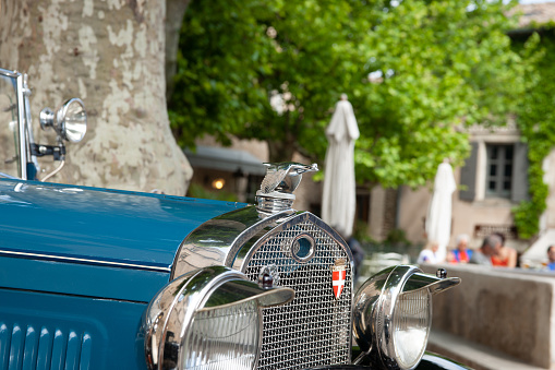 Gordes, France - MAy 1 2011; Bugatti Vintage blue car bonnet, grille  and lights in close-up parked in front historic and picturesque French walled town in stop-over in car rally.