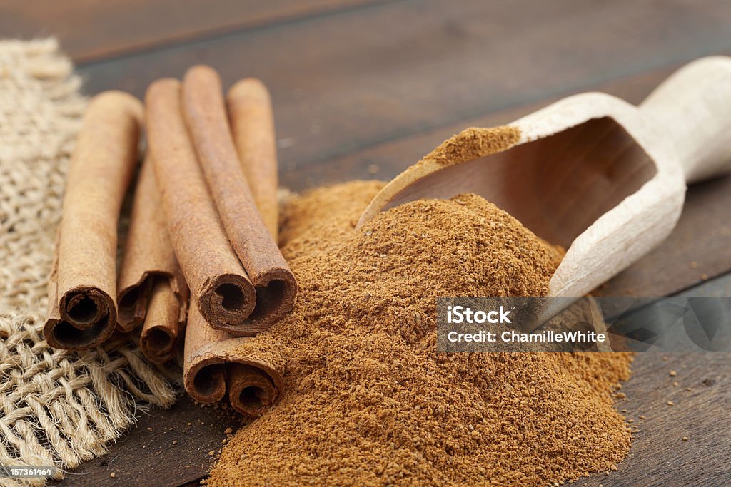 Cinnamon sticks and powder in wooden scoop Cinnamon sticks and cinnamon powder in wooden scoop Bag Stock Photo