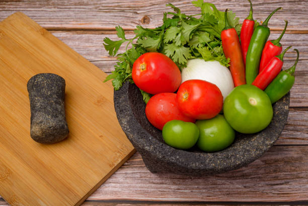 istock Molcajete with vegetables on wooden table. Ingredients for a hot sauce. 1573620788