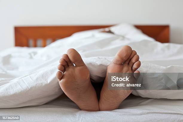 Close Up Of Two Feet In Bed Stock Photo - Download Image Now - Adult, Adults Only, Bed - Furniture